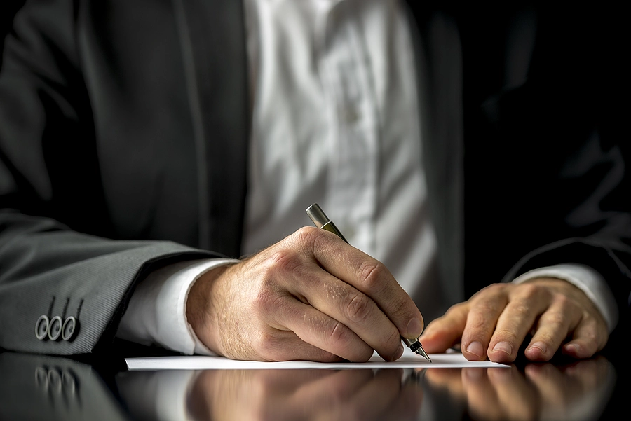 Suited person signing a document