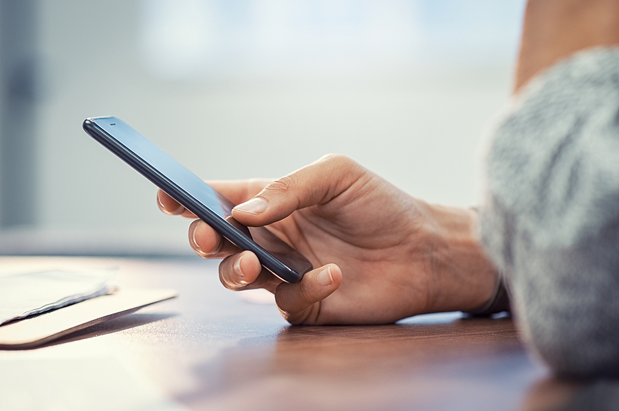 Closeup hand of woman using smartphone on wooden table. Business
